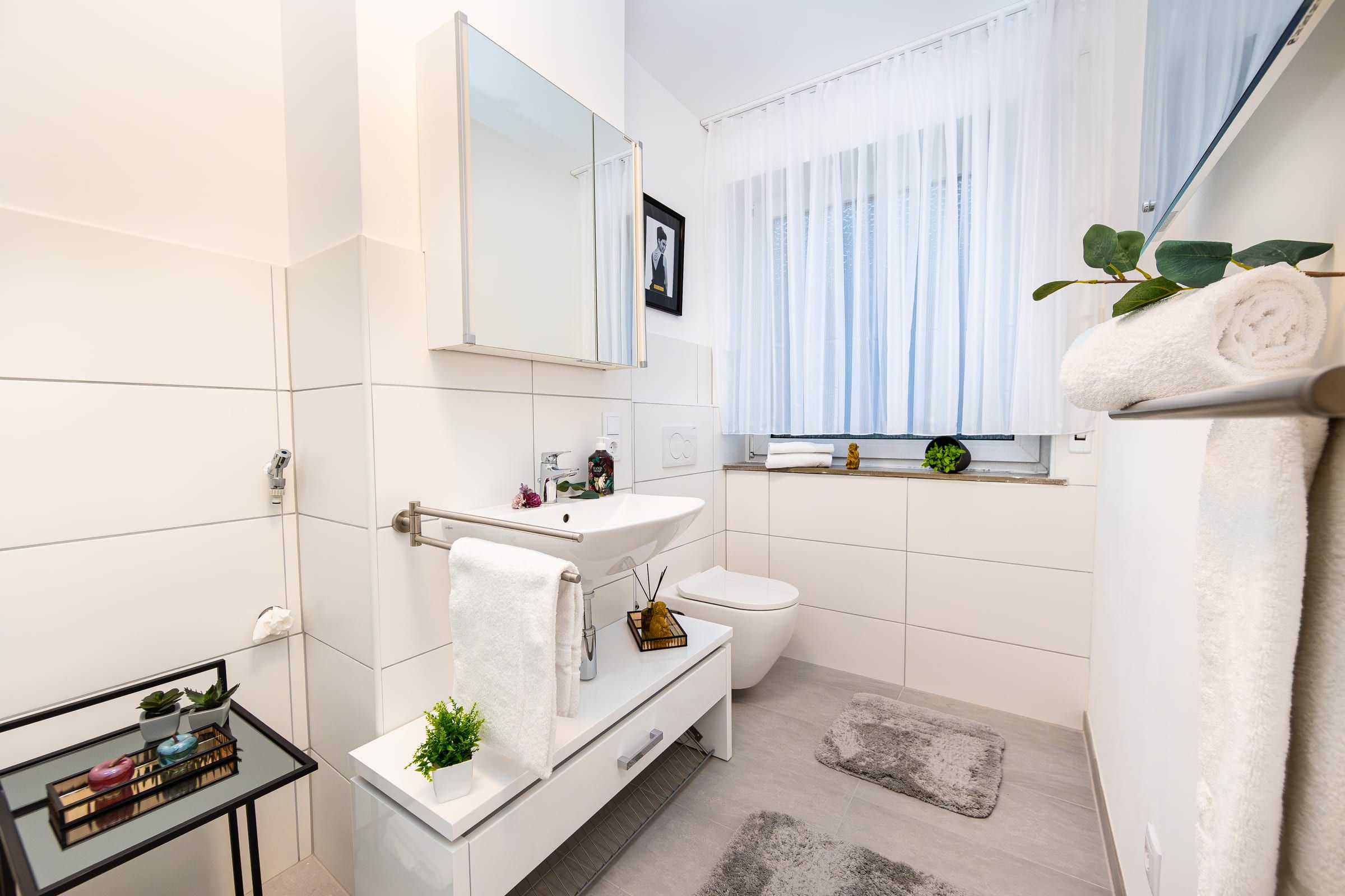 Bad mit Waschbecken, Toilette, Handtuchhalter und Fenster