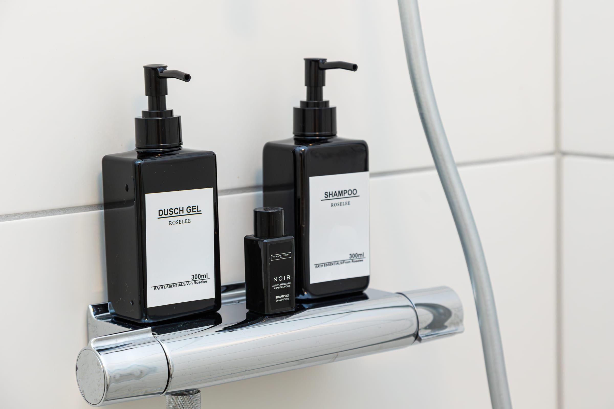 Duschgel und Shampoo in Pumpspendern auf der Ablage der Duscharmatur