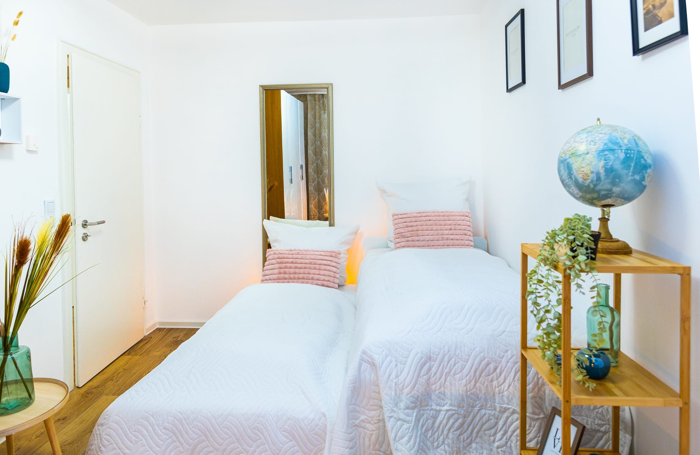 Schlafzimmer 2 mit zwei Einzelbetten nebeneinander und Holzregal mit Globus